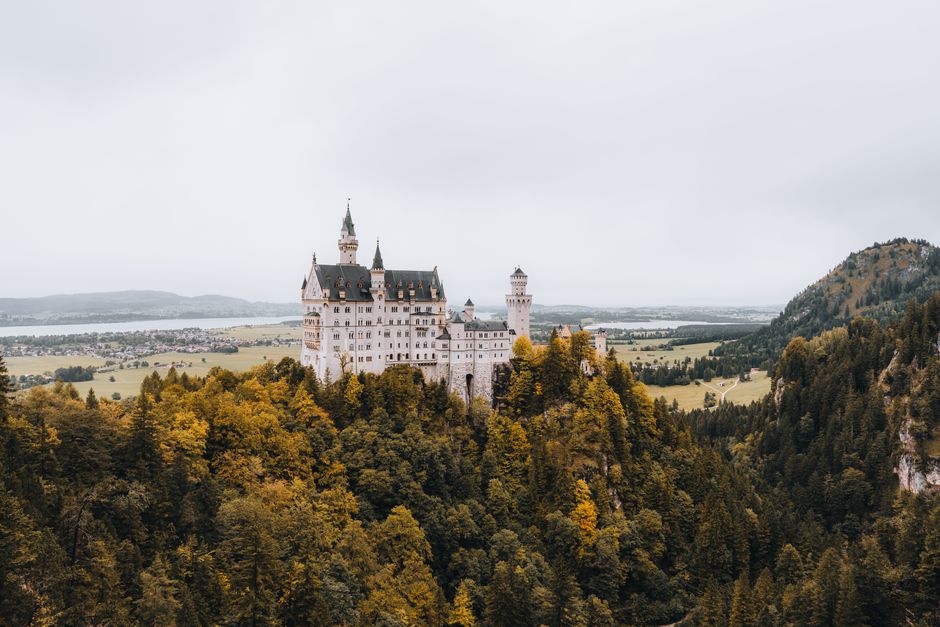 Stunning aerial view of Neuschwanstein Castle amid autumn foliage in Bavaria, Germany.