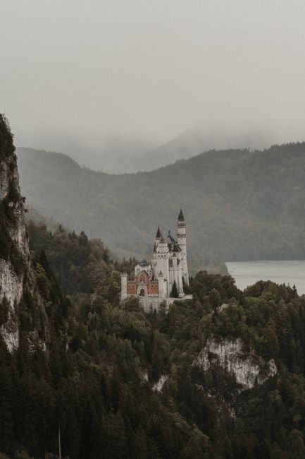A stunning aerial shot of Neuschwanstein Castle surrounded by lush greenery and mountains in Bavaria, Germany.