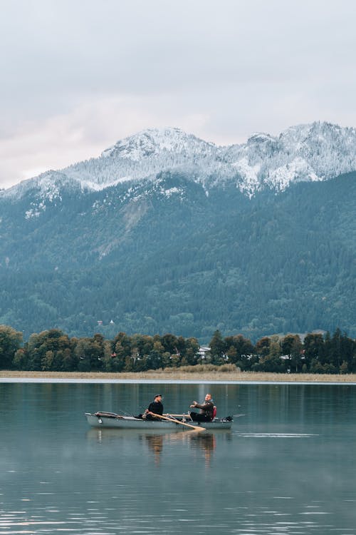 Men on Boat on Lake by Rocky Mountain