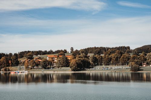 Free A peaceful lakeside scene with sailboats and autumn trees in Baiern, Germany. Stock Photo