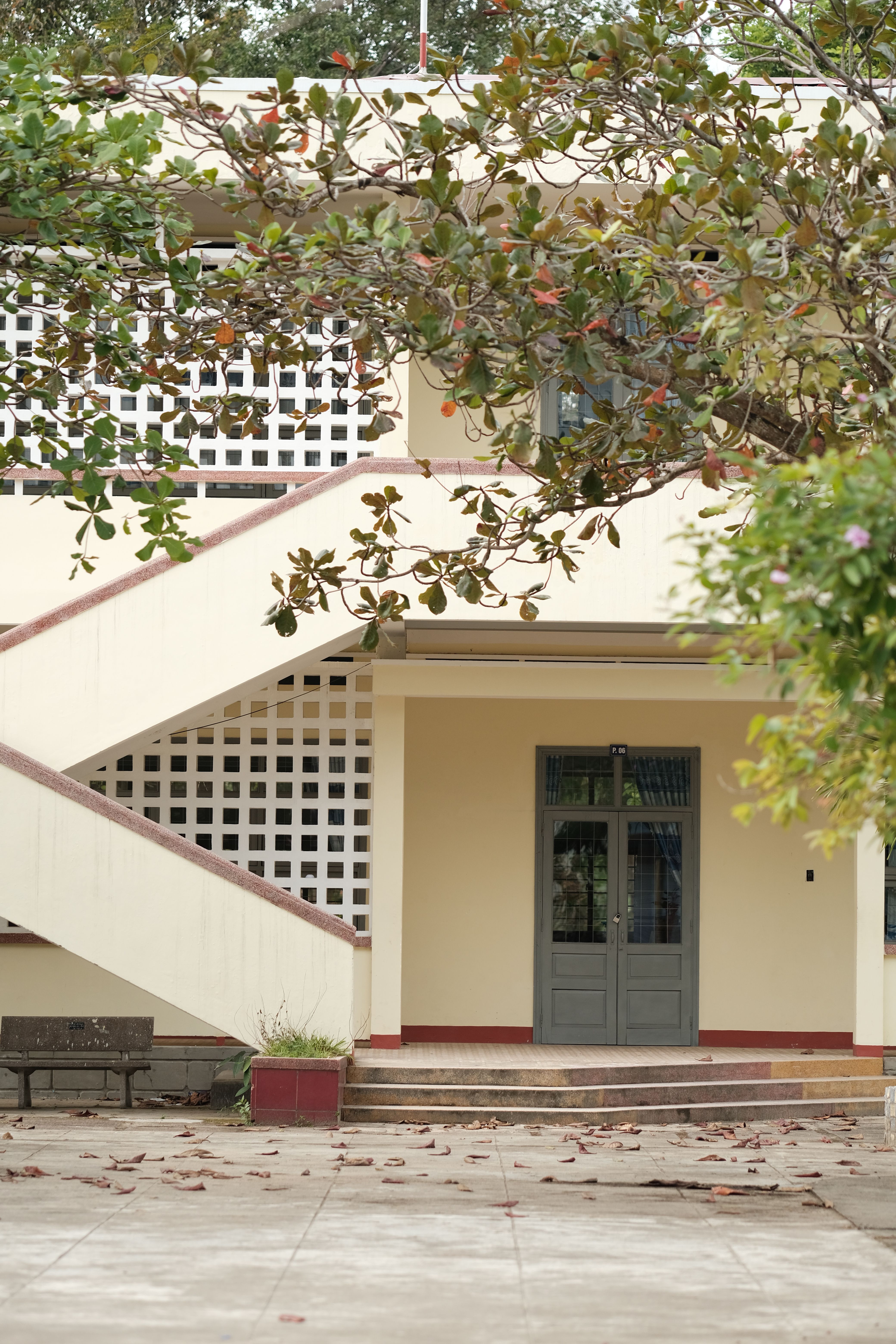 Elegant exterior of a two-story building with stairway and foliage.
