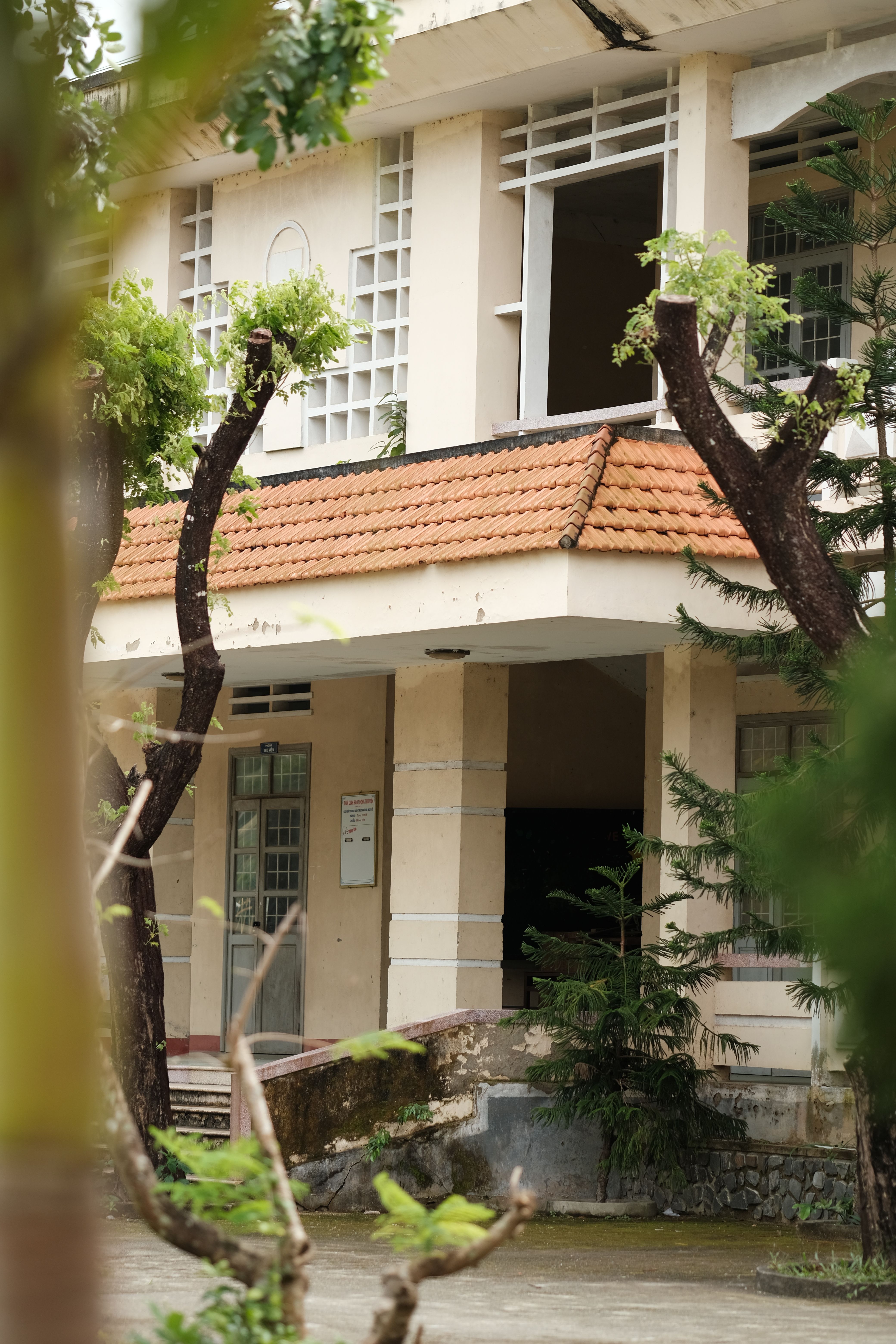 A quaint building exterior featuring a tiled roof and an inviting entrance surrounded by lush greenery.