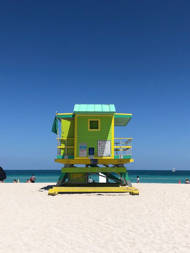 A lime and turquoise lifeguard tower on Miami Beach under a deep blue sky