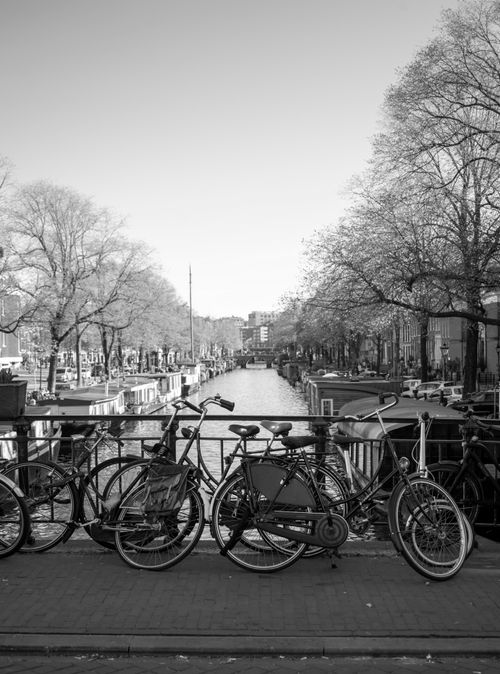 Free Black and white photo of bicycles on a bridge over an Amsterdam canal, capturing urban and architectural beauty. Stock Photo