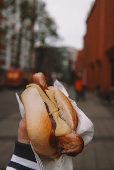 Tasty hot dog with mustard held on a street in Münster, showcasing urban street food culture.