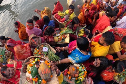 Group of people in colorful attire celebrating Chhath Puja by the river in Kolkata.
