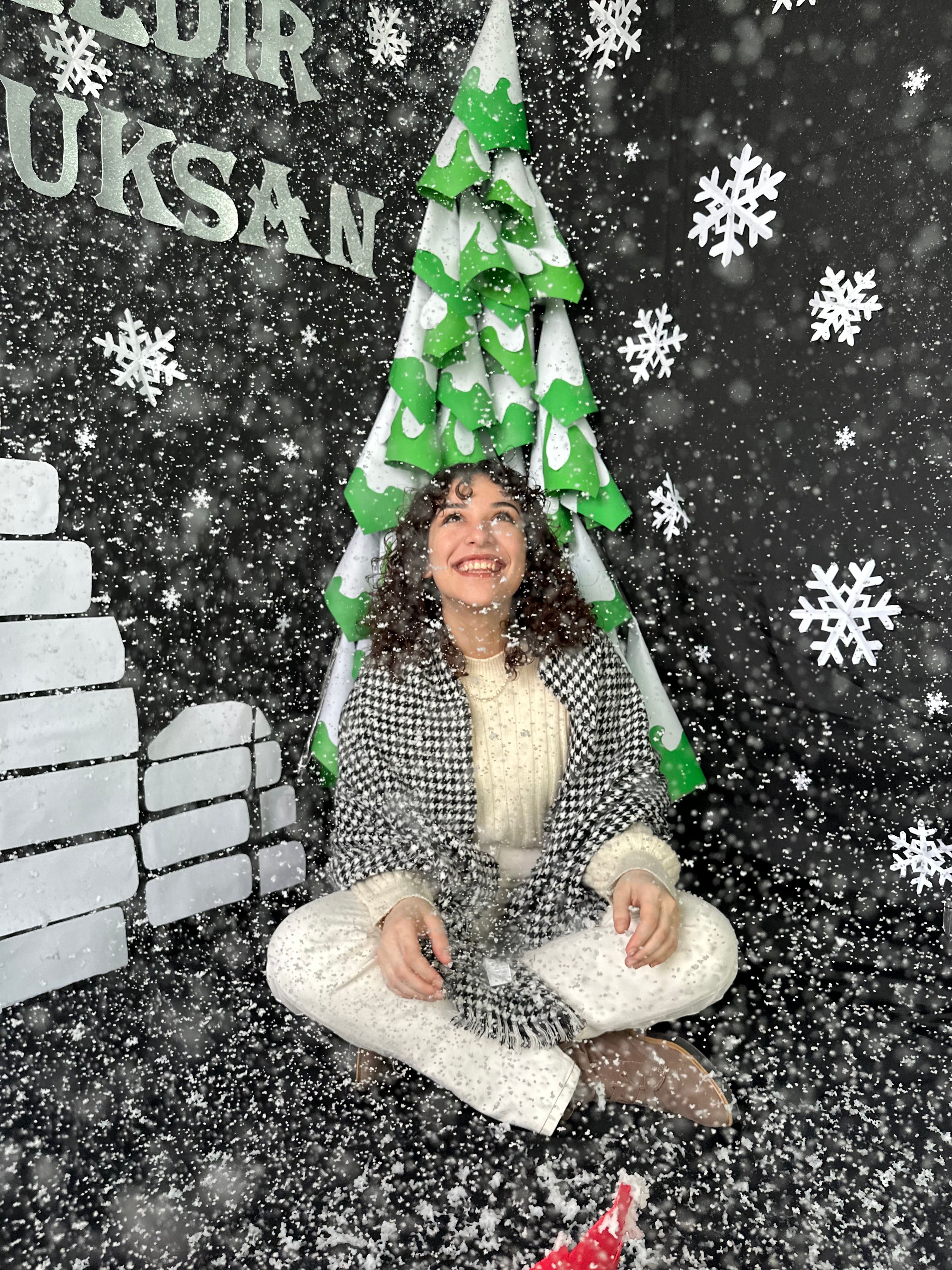 Smiling woman enjoying artificial snow in a festive indoor setting, Korkuteli.