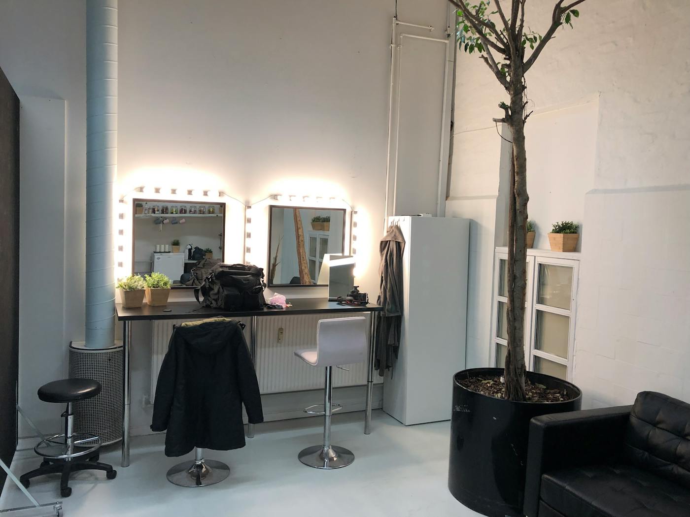 A salon-style vanity station with mirrors and bright lights