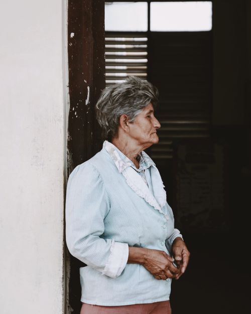 Free Portrait of an elderly woman standing in a doorway, showcasing grace and elegance. Stock Photo