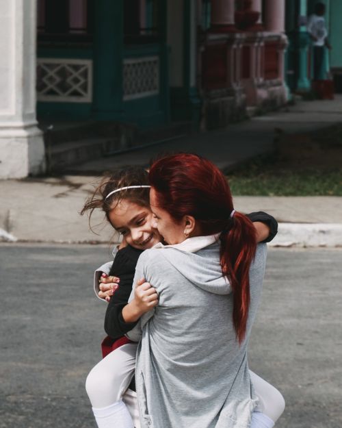 Free A joyful moment between mother and daughter embracing on a sunny city street. Stock Photo
