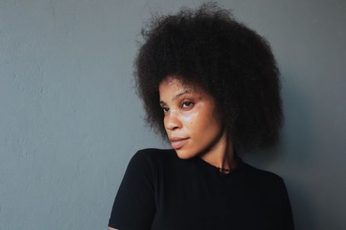 Free Striking studio portrait of a woman with a natural afro, exuding confidence. Stock Photo