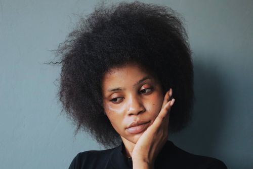 Free Portrait of an African woman with afro hair, posing thoughtfully in a studio. Stock Photo