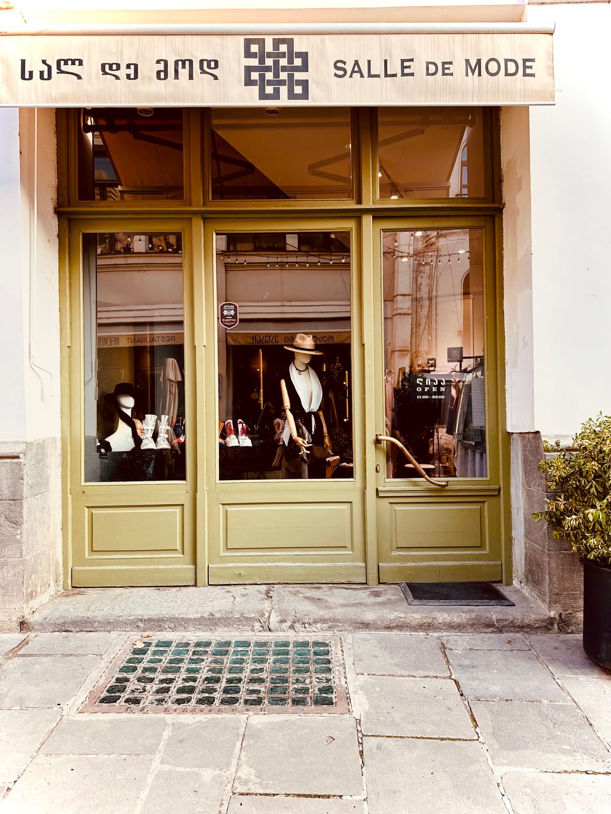 Boutique storefront with mannequins and elegant fashion display on a city sidewalk.