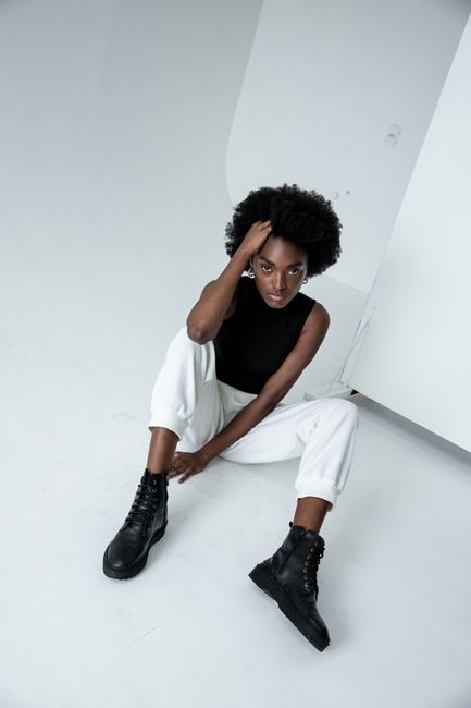 African woman with afro hairstyle posing fashionably in a minimalist São Paulo studio setting.