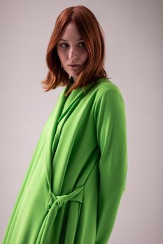Stylish portrait of a young woman wearing a green dress, captured in a studio.