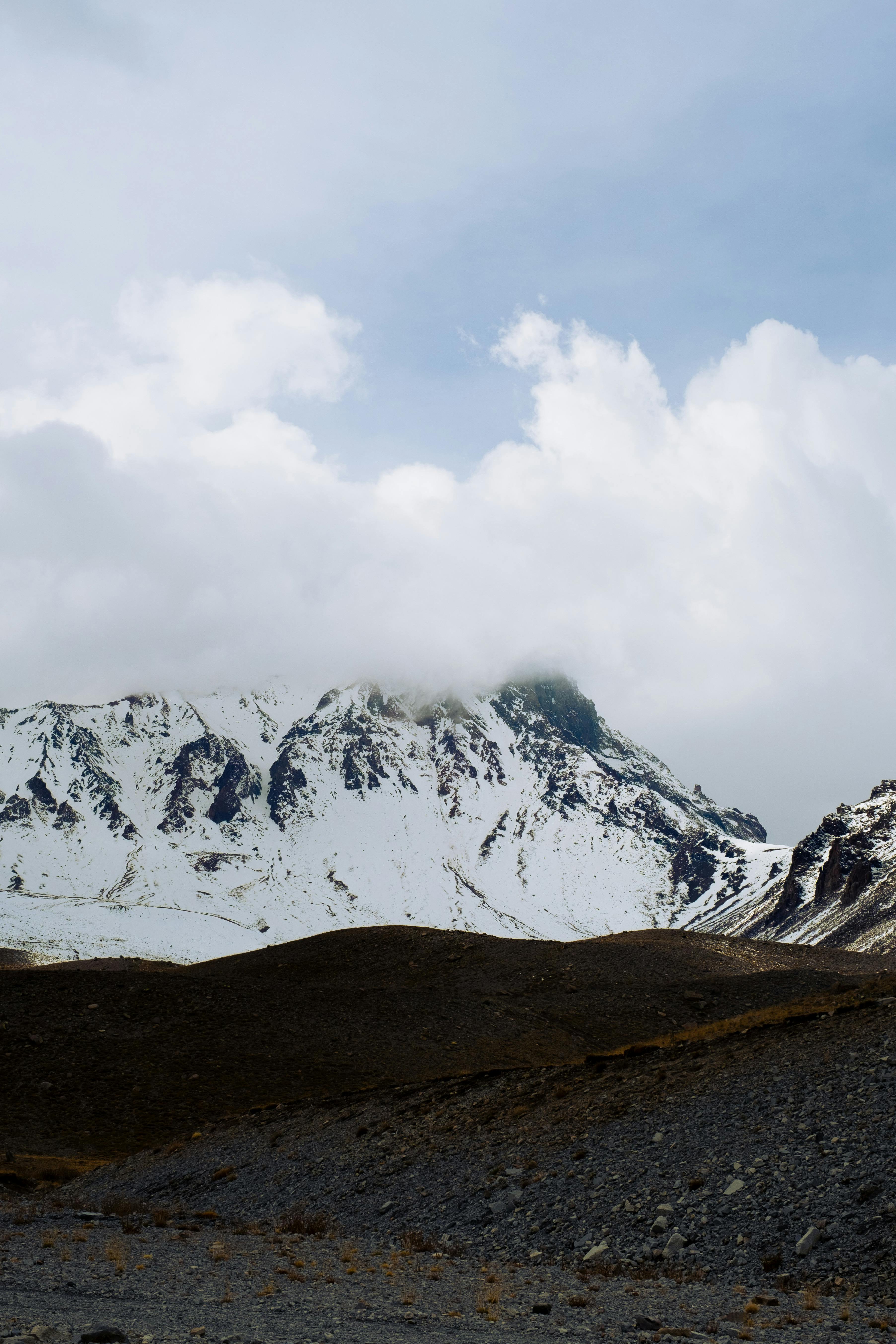 Majestic snow-covered Mount Erciyes under cloudy skies in Kayseri, Türkiye.