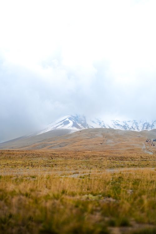 Free Serene landscape of snow-capped mountains and lush fields in Kayseri, Türkiye, under cloudy skies. Stock Photo