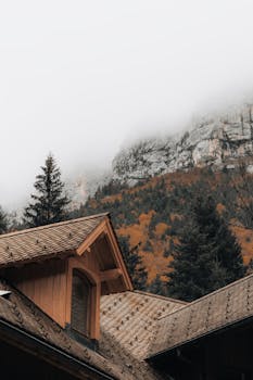 Misty autumn view of village roofs and mountains in Saint-Pierre-d'Entremont, France.