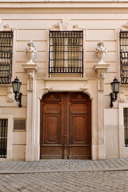 Classic architectural facade with wooden doors and cobblestone street in Vienna, Austria.