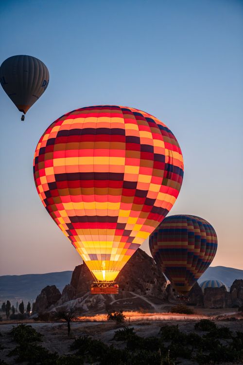 Free Vibrant hot air balloons illuminated against the Cappadocia landscape during a beautiful sunset in Türkiye. Stock Photo
