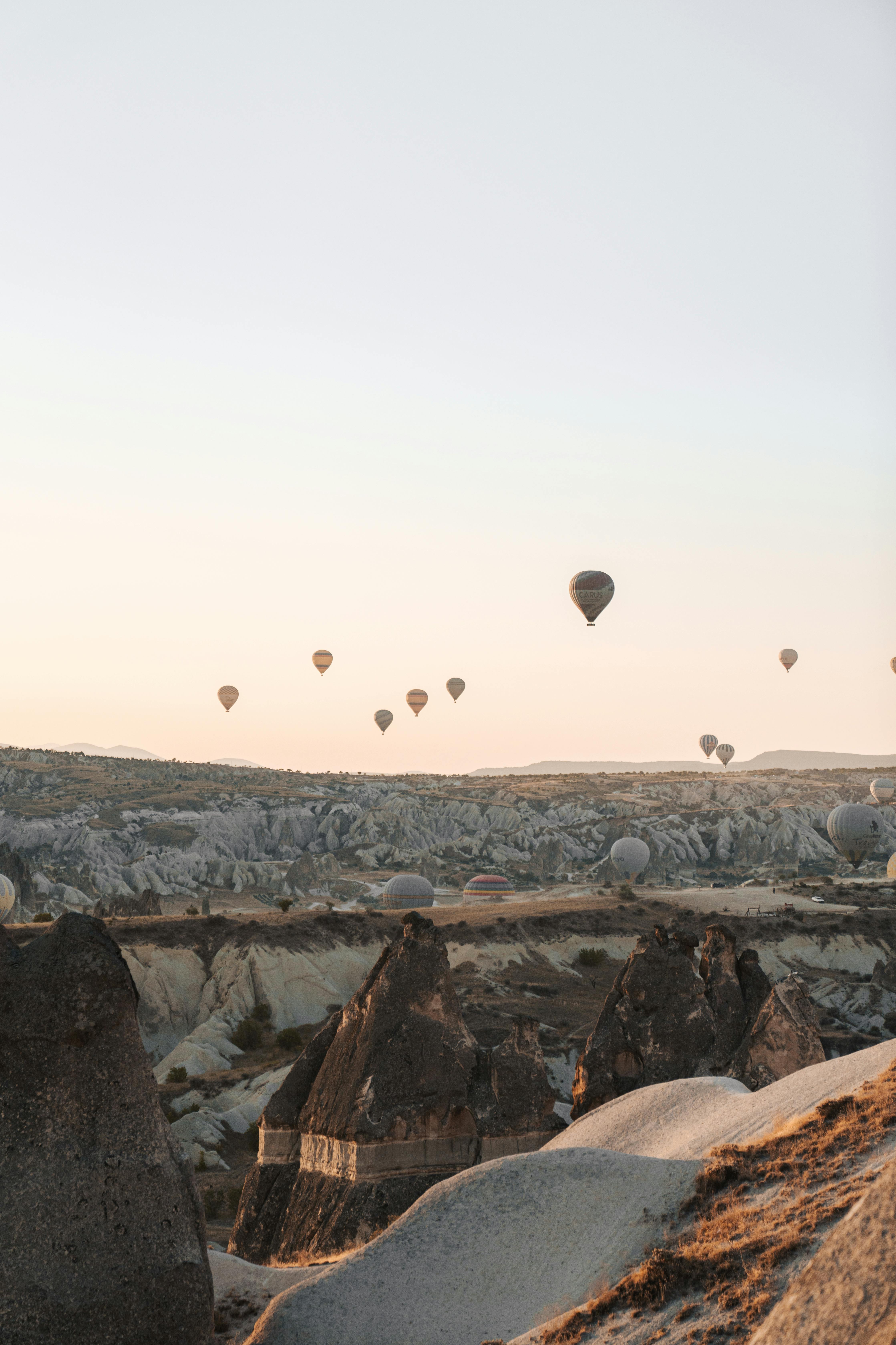 Scenic view of hot air balloons floating over Cappadocia's unique landscape at sunrise, Turkey.