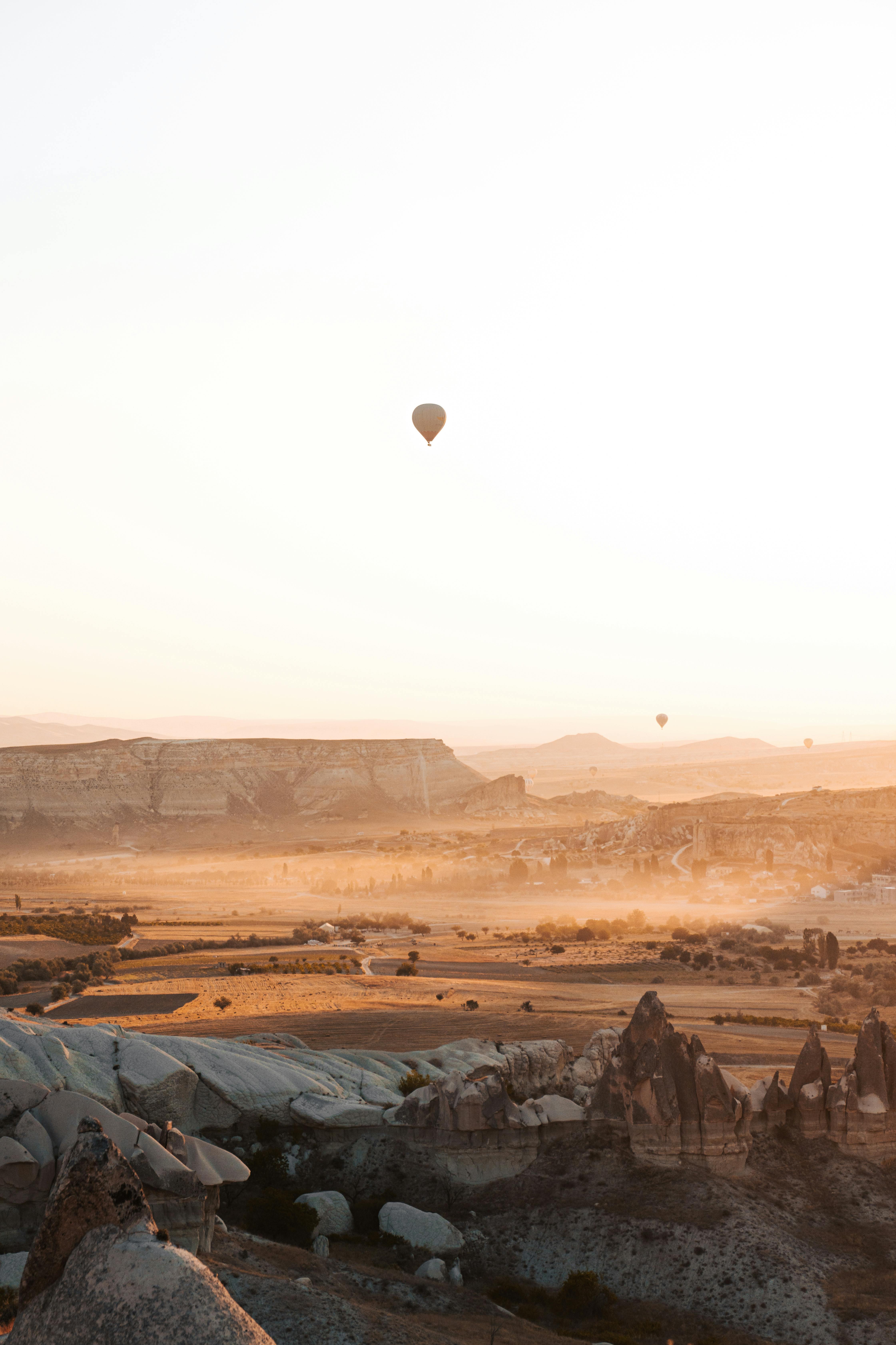 Balões de Ar Quente em Cappadocia flutuando sobre formações rochosas em Cappadocia, Turquia ao pôr do sol