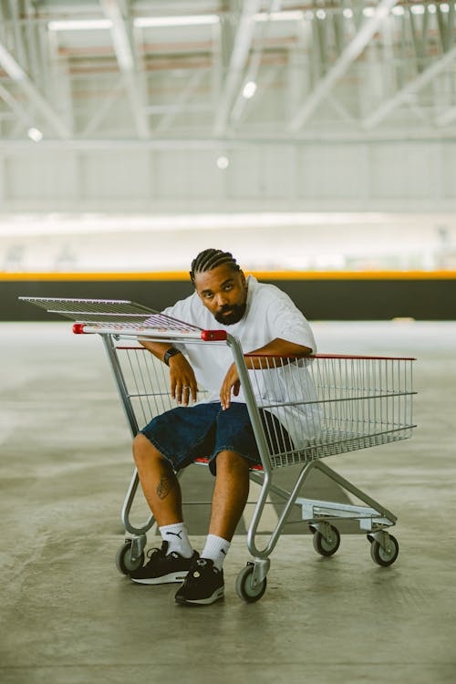 Free Man in Shorts Sitting in Shopping Cart Stock Photo