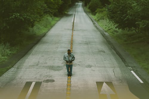 High Angle Shot of a Man Standing on an Asphalt Road 