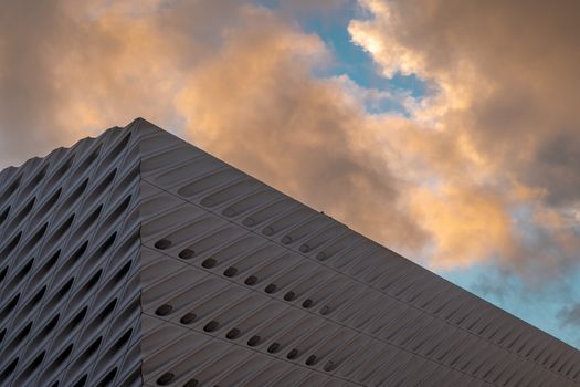 A striking modern architectural facade with a dynamic sky backdrop at sunset.