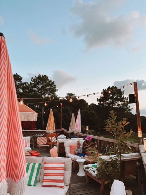 Free Relaxing outdoor café terrace with colorful seating and string lights under the evening sky. Stock Photo