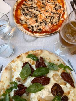 Savor two freshly served Italian pizzas topped with mushrooms and sundried tomatoes, ideal for a casual dining experience.