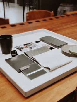 A collection of contemporary design samples and swatches arranged on a tray on a wooden desk.