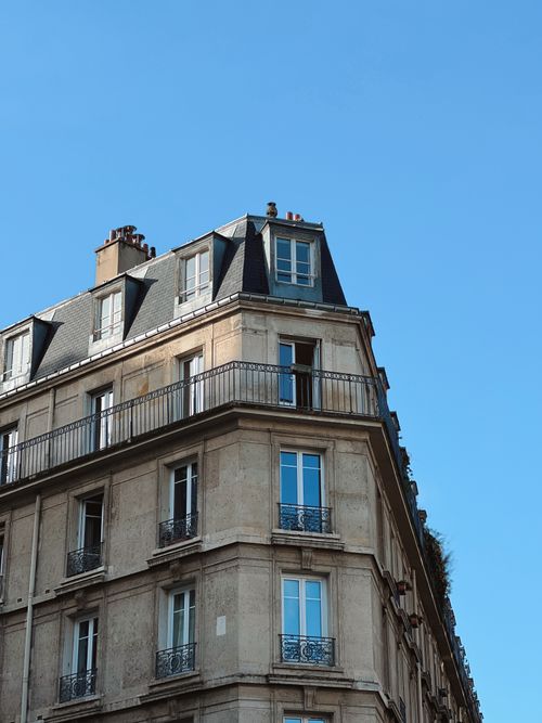 Free Elegant corner building in Paris with Haussmannian architectural style against a clear blue sky. Stock Photo