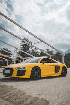 A yellow sports car parked on a scenic street in Carinthia, Austria under a partly cloudy sky.