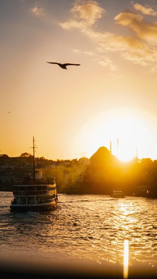 Free A serene sunset view over Istanbul harbor featuring a boat and mosque silhouette. Stock Photo