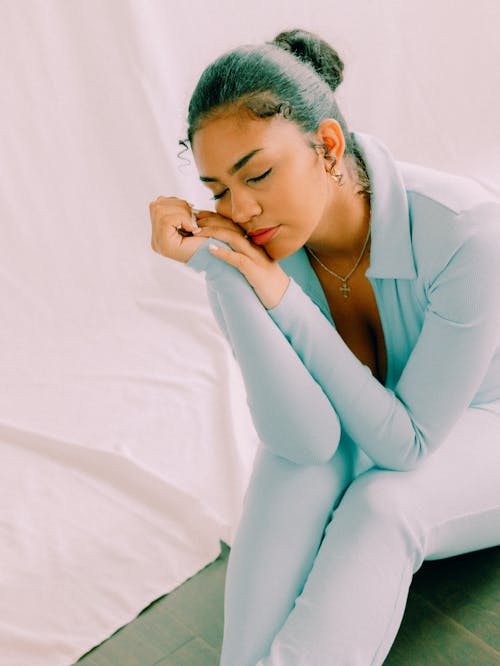 A woman in a blue jumpsuit sitting on the floor