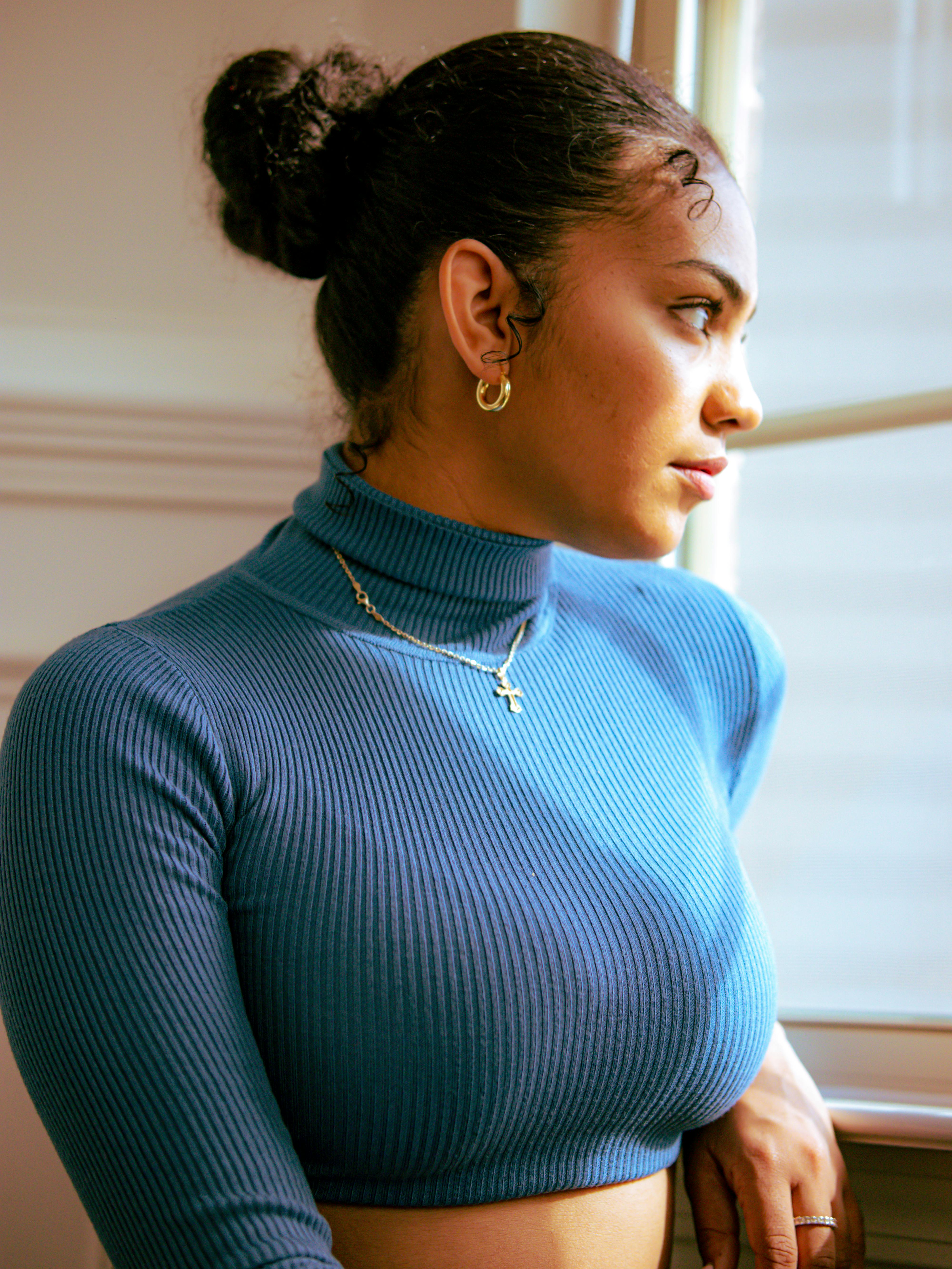 woman wearing blue turtle neck looking out the window