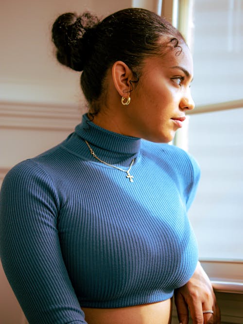 Woman wearing blue turtle neck looking out the window 