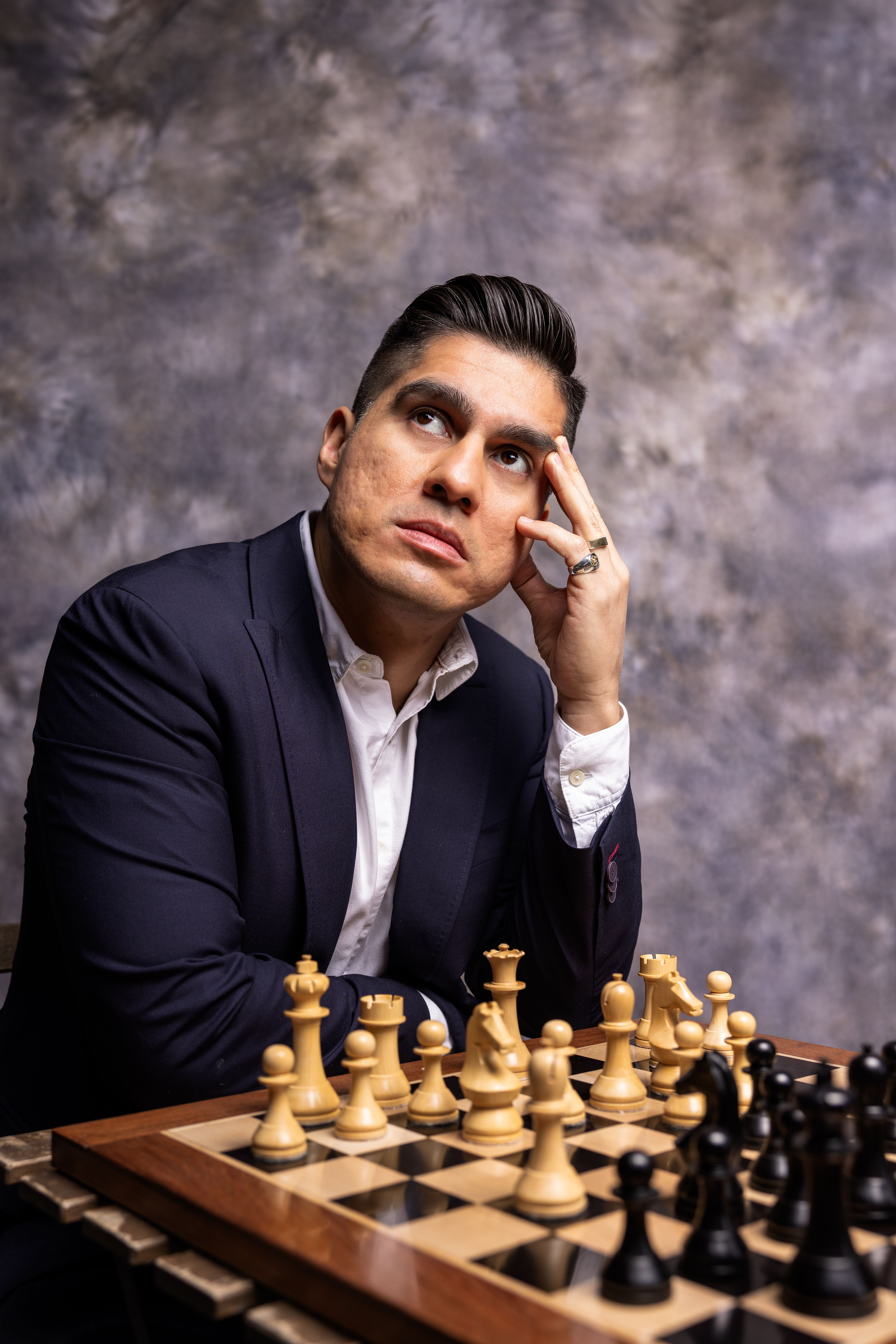 Man in a Suit Sitting beside a Chess Board