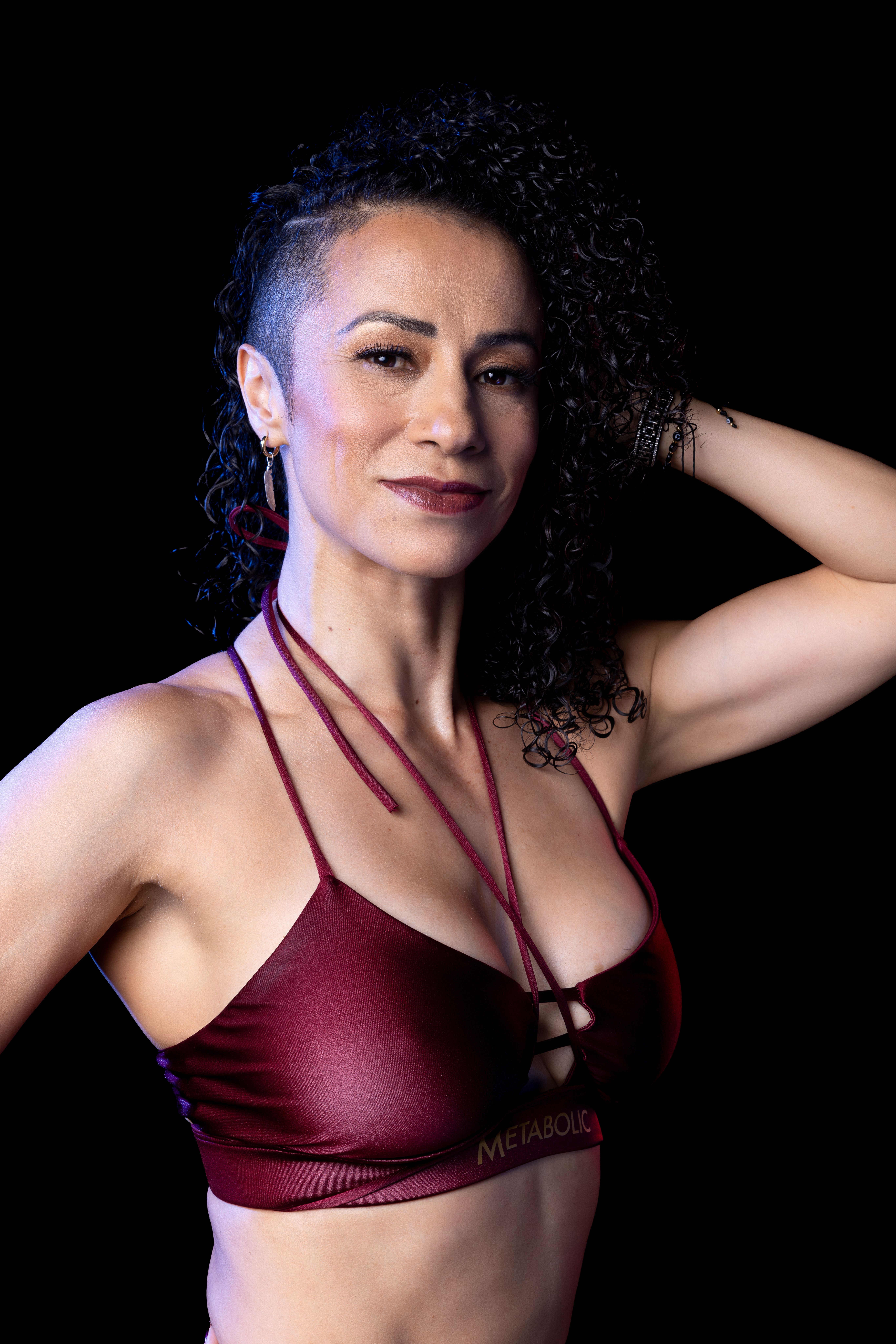Portrait of a confident woman posing with a smile against a black background.