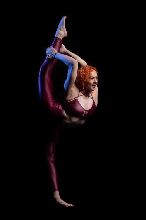 Free A graceful redhead gymnast performing an elegant leg stretch in sportswear. Stock Photo