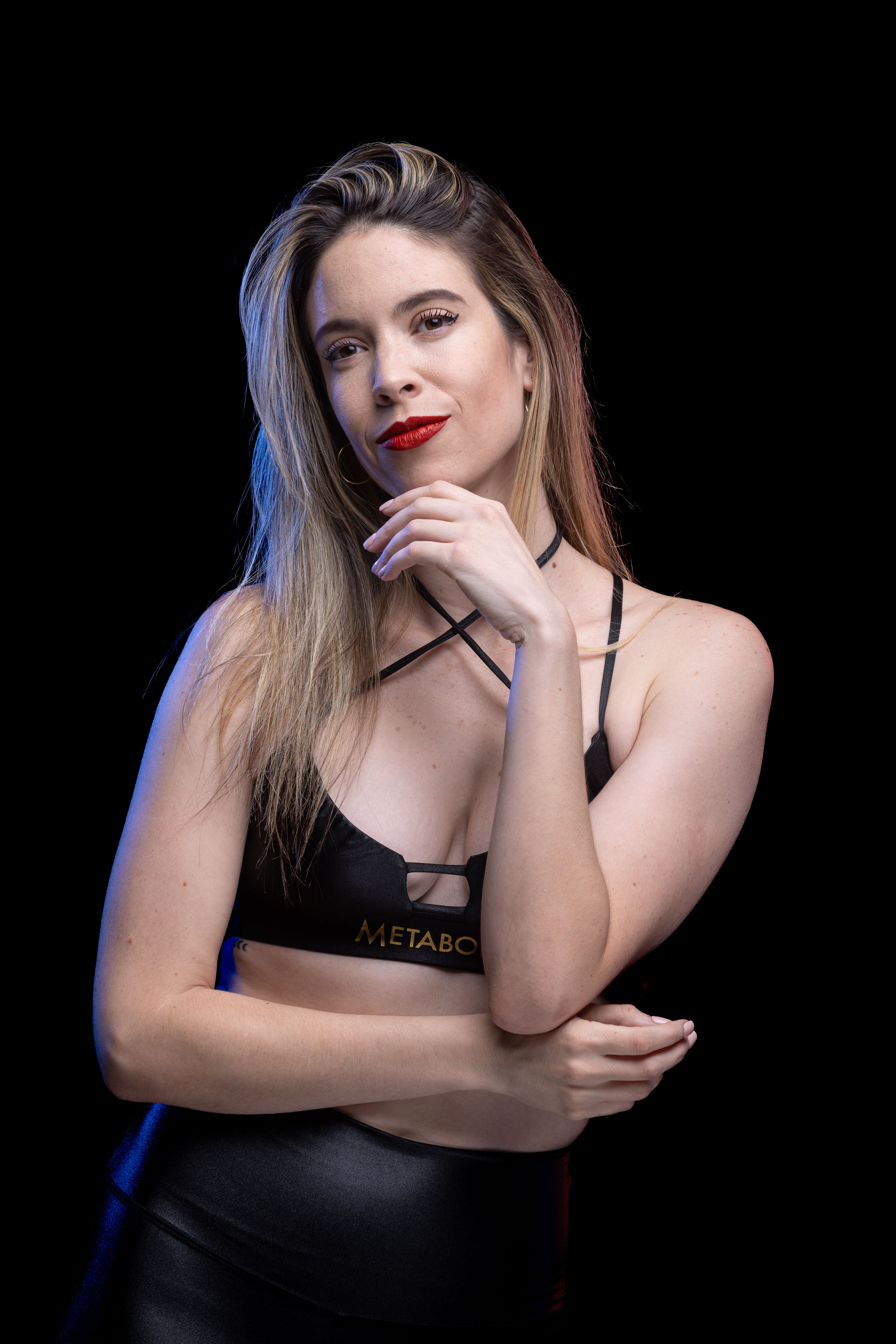 Portrait of a woman with red lipstick and blonde hair posing against a black background.