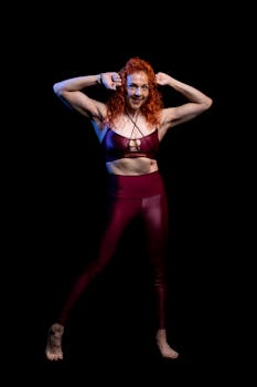 Athletic woman in sportswear flexing muscles with a confident smile during a studio shoot.