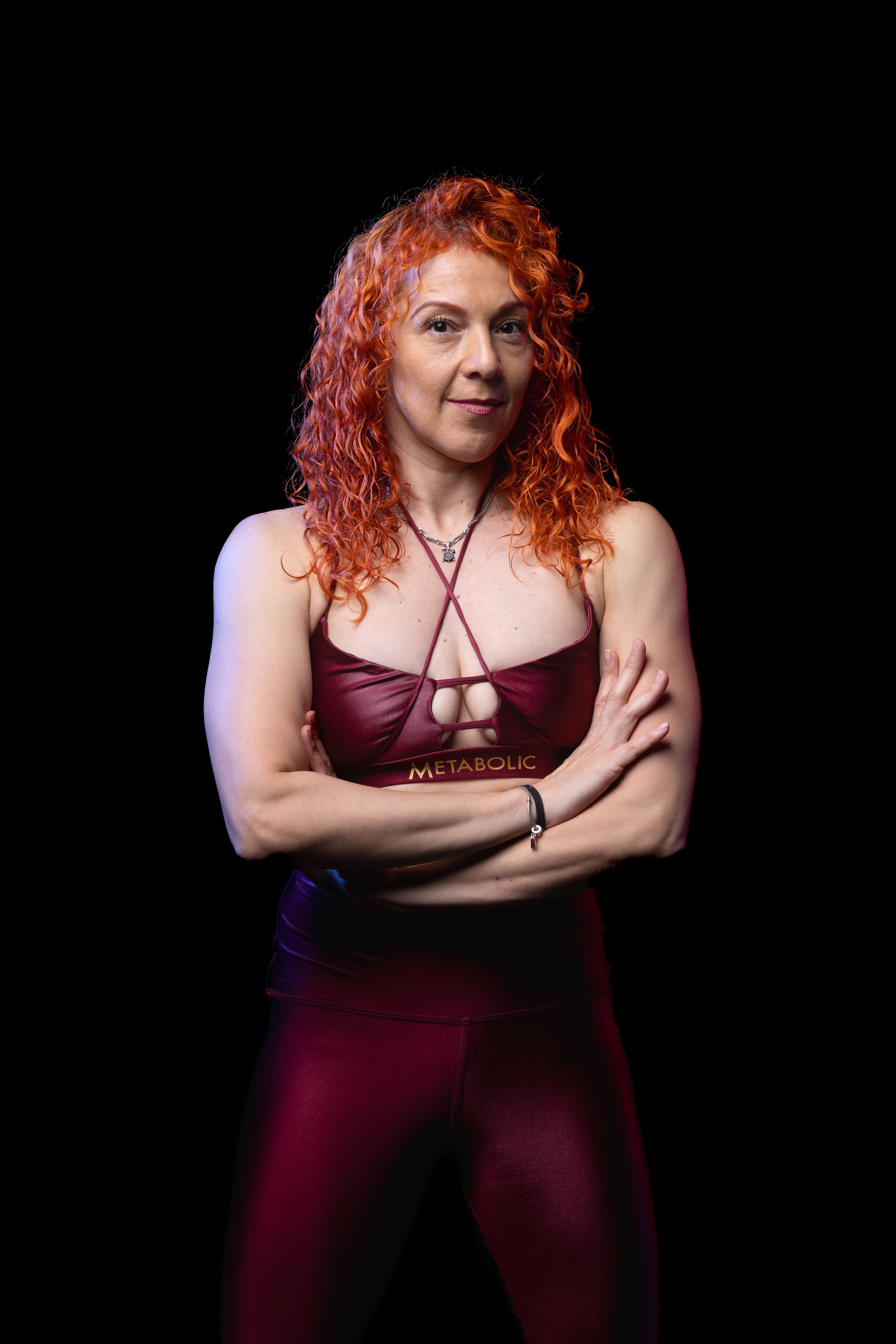 Portrait of a fit woman in sportswear posing confidently with a black background, ideal for fitness or fashion themes.