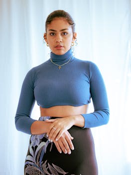 Portrait of a stylish woman in a blue turtleneck with floral skirt, radiating elegance.