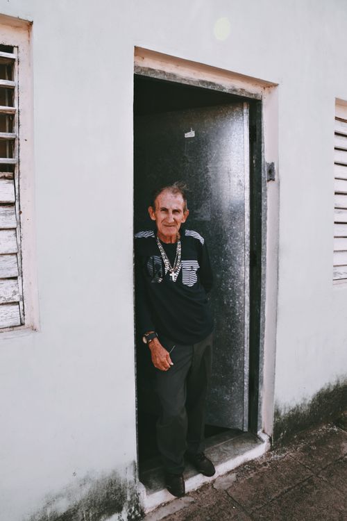 Free An elderly man standing in a doorway of a modest house, reflecting peaceful retirement life. Stock Photo