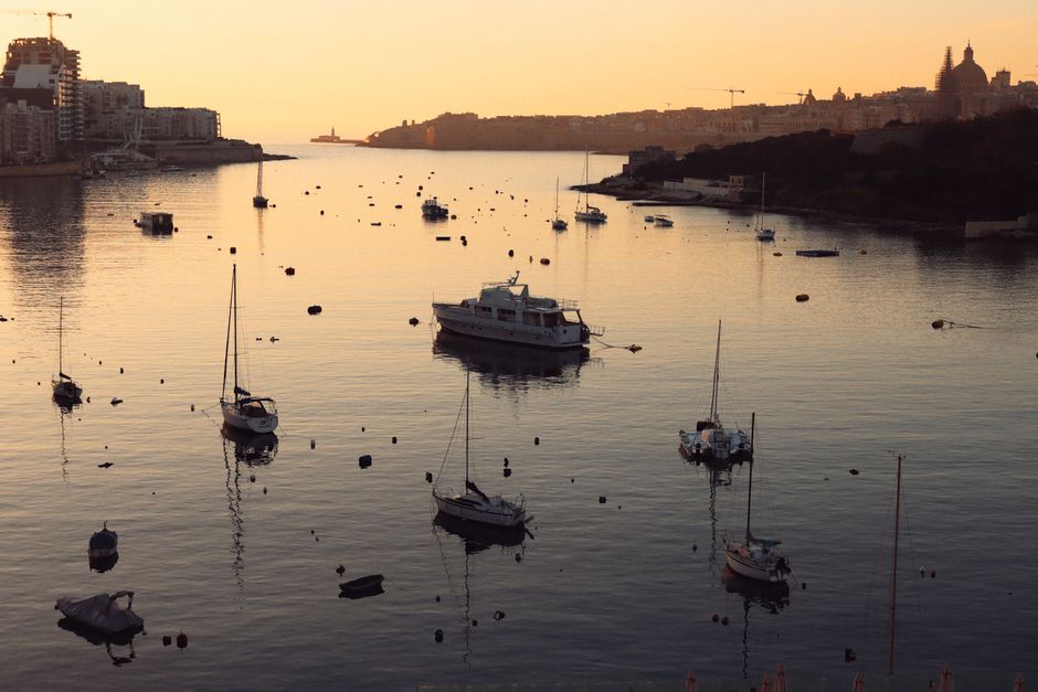 Stunning Malta Private Boat Tour: Gozo, Comino, Blue Lagoon Crystal Lagoon Review 2026 - Tranquil harbor scene in Valletta, Malta at sunset with boats reflecting on calm waters.