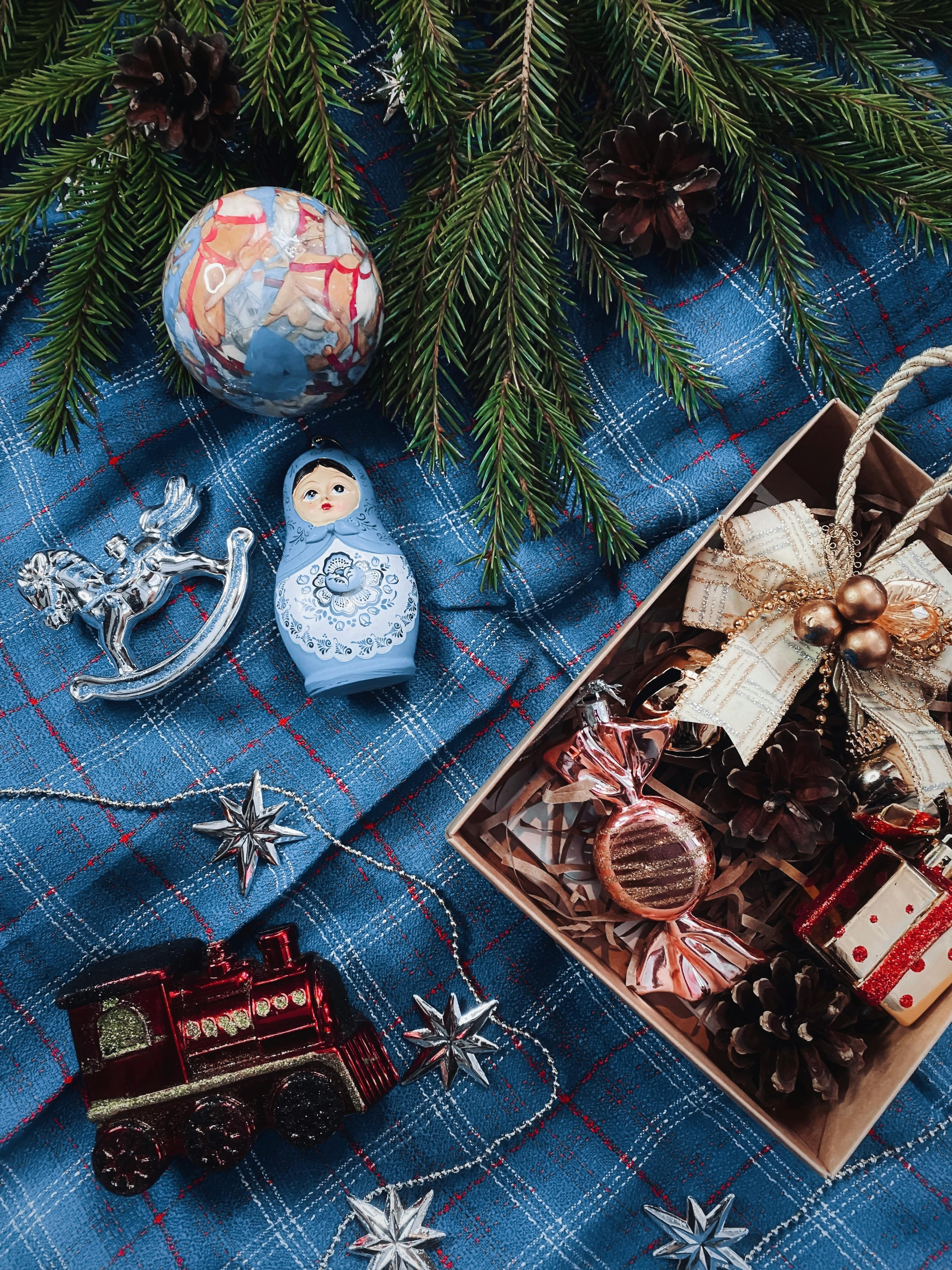 A Christmas-themed arrangement with decorations, pine needles, and festive ornaments on a blue blanket.