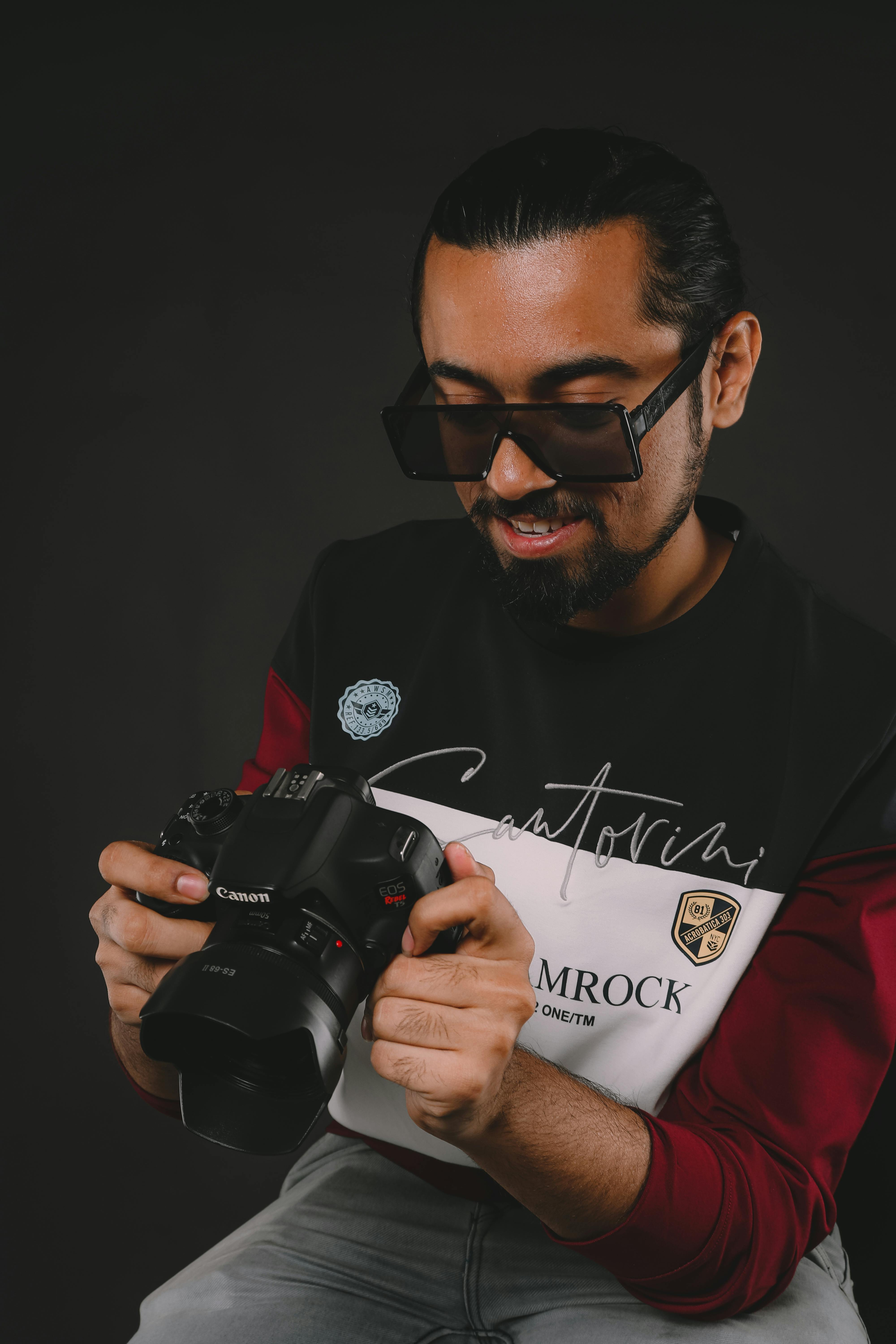 Portrait of a smiling man holding a professional camera in a studio setting.