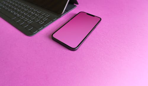 A Smartphone with a Purple Lockscreen Lying next to a Keyboard 